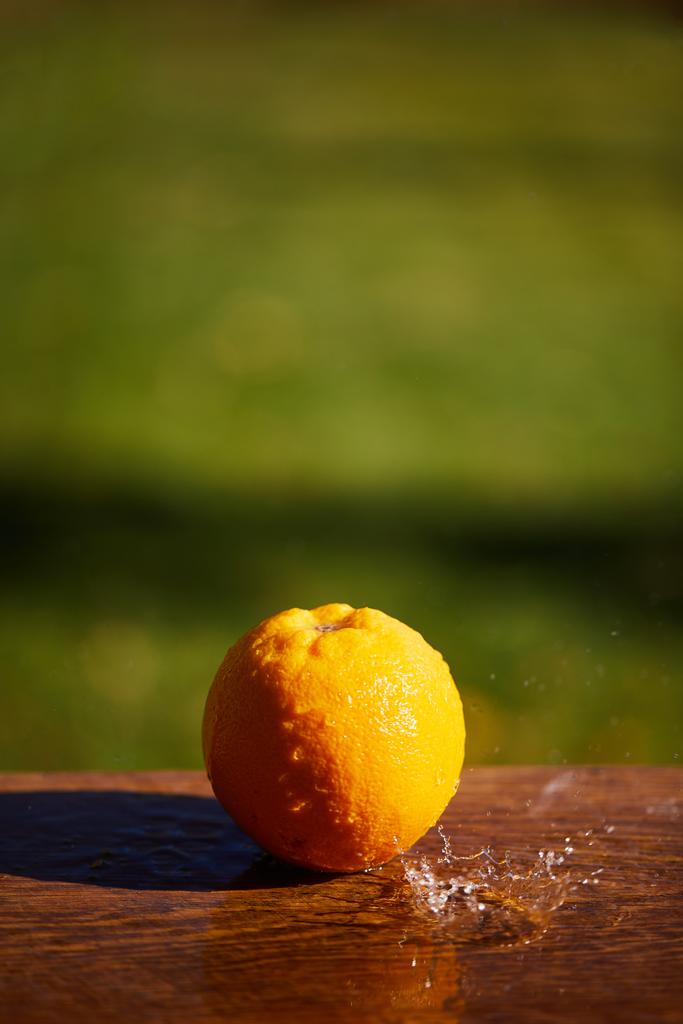 selective focus of whole and wet orange on wooden surface  - 写真・画像