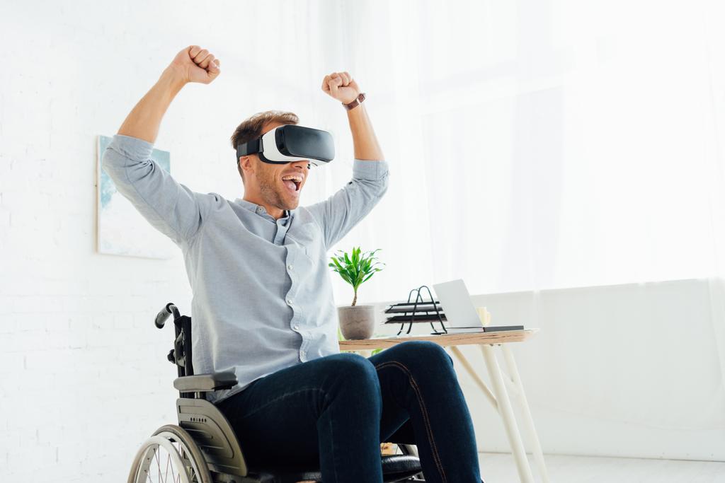 Homme joyeux en fauteuil roulant en utilisant casque de réalité virtuelle dans le salon
 - Photo, image