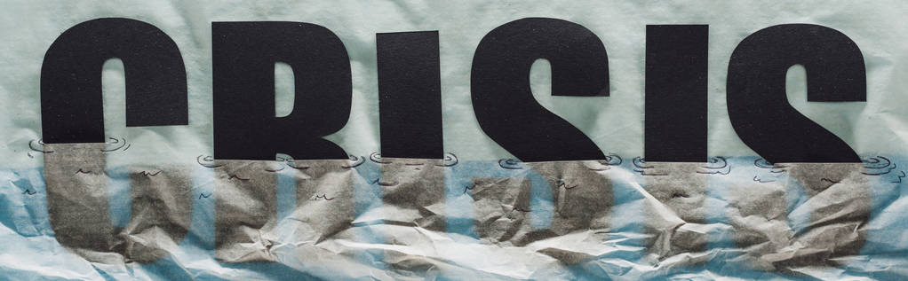 colpo panoramico di crisi di parola nera che affonda nella carta che simboleggia l'acqua su sfondo di carta grigia
 - Foto, immagini