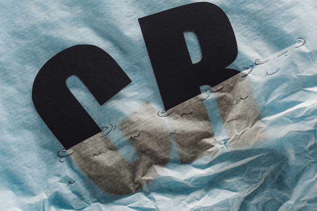 черные буквы c и r, погруженные в бумагу, символизирующие воду на сером бумажном фоне
 - Фото, изображение