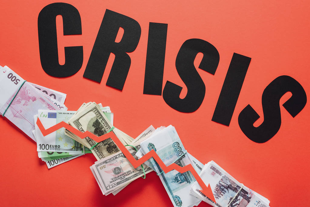 top view of black paper cut word crisis, and recession arrow on dollar, euro and ruble banknotes on red background - Photo, Image
