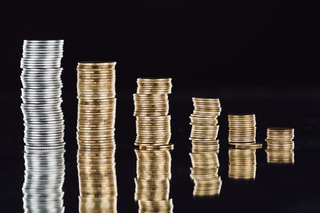 stacks of silver and golden coins on surface with reflection isolated on black - Photo, Image