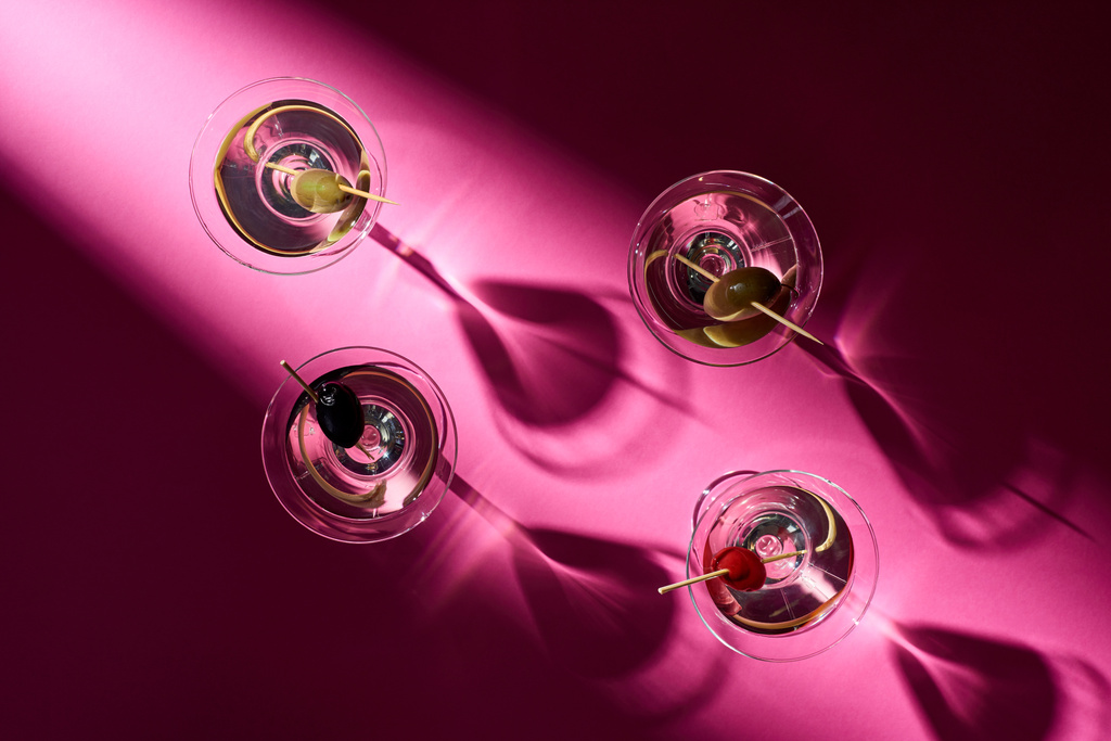 Bovenaanzicht van cocktails met olijven op roze achtergrond met schaduwen - Foto, afbeelding