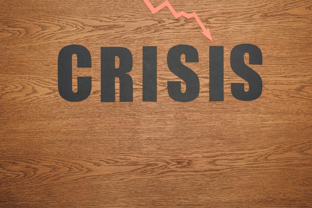 Draufsicht auf schwarzes Papier geschnitten Wort Krise und Rezession Pfeil auf Holzoberfläche mit Kopierraum - Foto, Bild