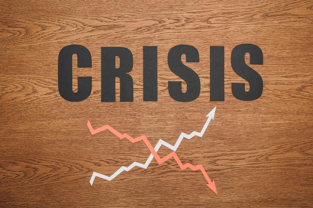 Draufsicht auf schwarzes Papier geschnitten Wort Krise nahe Anstieg und Rezession Pfeile auf hölzernen Schreibtisch - Foto, Bild