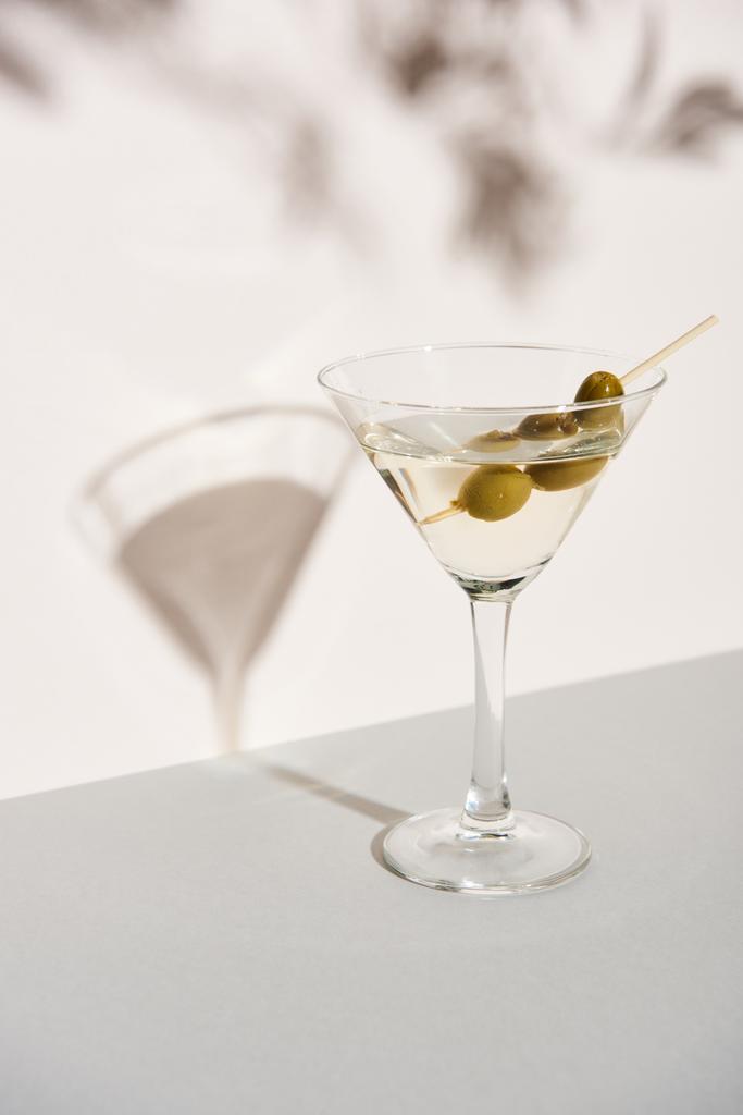 Martini con aceitunas sobre fondo blanco con sombra
 - Foto, Imagen