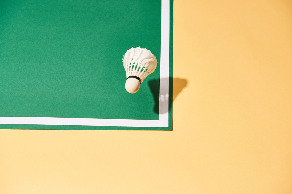 Hochwinkelaufnahme von Federball auf grünem Platz und gelber Oberfläche - Foto, Bild