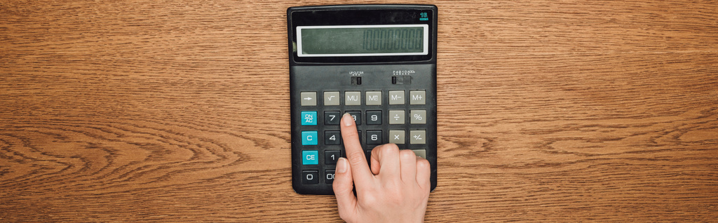 vista parcial de la mano femenina en la calculadora con cien mil en exhibición en escritorio de madera, plano panorámico
 - Foto, imagen