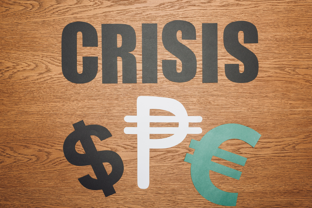 vista superior del dólar, el peso y el euro símbolos de corte de papel, y la palabra crisis en escritorio de madera
 - Foto, imagen