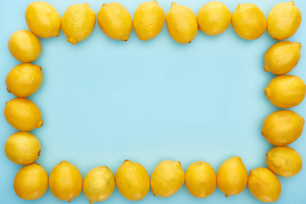 コピースペースのある青の背景に熟した黄色のレモンの正方形のフレーム - 写真・画像
