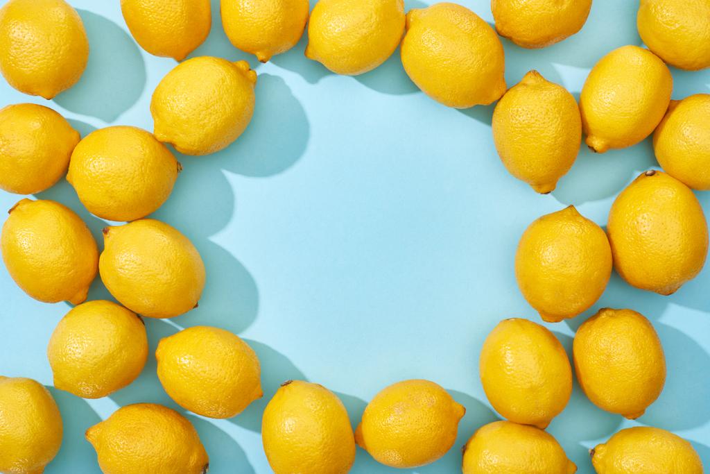 top view of ripe yellow lemons on blue background with shadows and copy space - Photo, Image