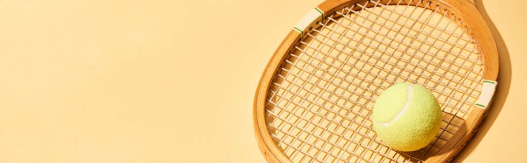 raquete de tênis de madeira e bola no fundo amarelo, tiro panorâmico
 - Foto, Imagem