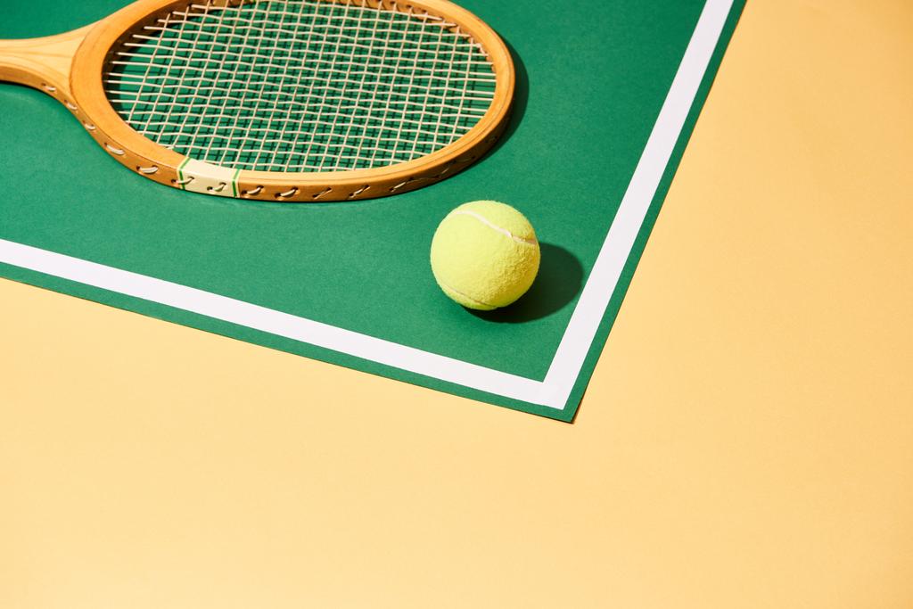 緑と黄色の背景にテニスボールと木製ラケット - 写真・画像