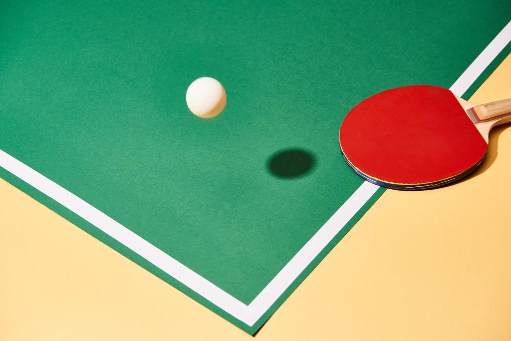 Racchetta da ping pong rossa e palla su tavolo pagante e superficie gialla
  - Foto, immagini