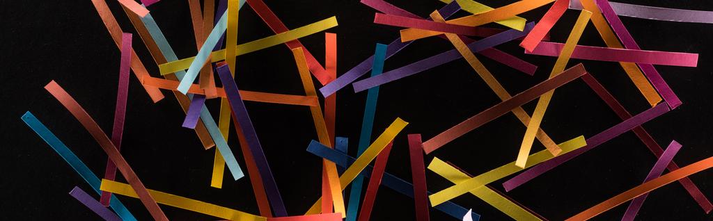 bovenaanzicht van veelkleurige abstracte lijnen verspreid over zwarte achtergrond, verbindings- en communicatieconcept - Foto, afbeelding