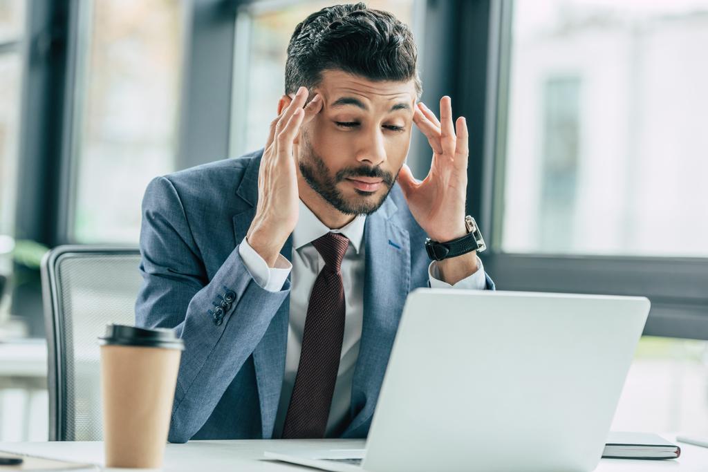 fáradt üzletember kéz a kézben a fej, miközben ül a munkahelyen, és szenved fejfájás - Fotó, kép