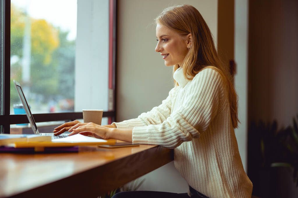 Onnellinen nainen vastaa sähköposteihin tietokoneellaan
 - Valokuva, kuva