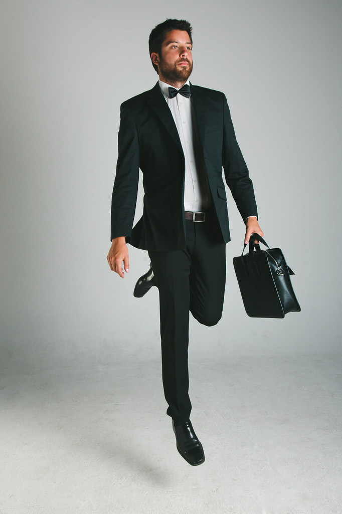 stijlvolle jonge man met zwart pak en aktentas. - Foto, afbeelding