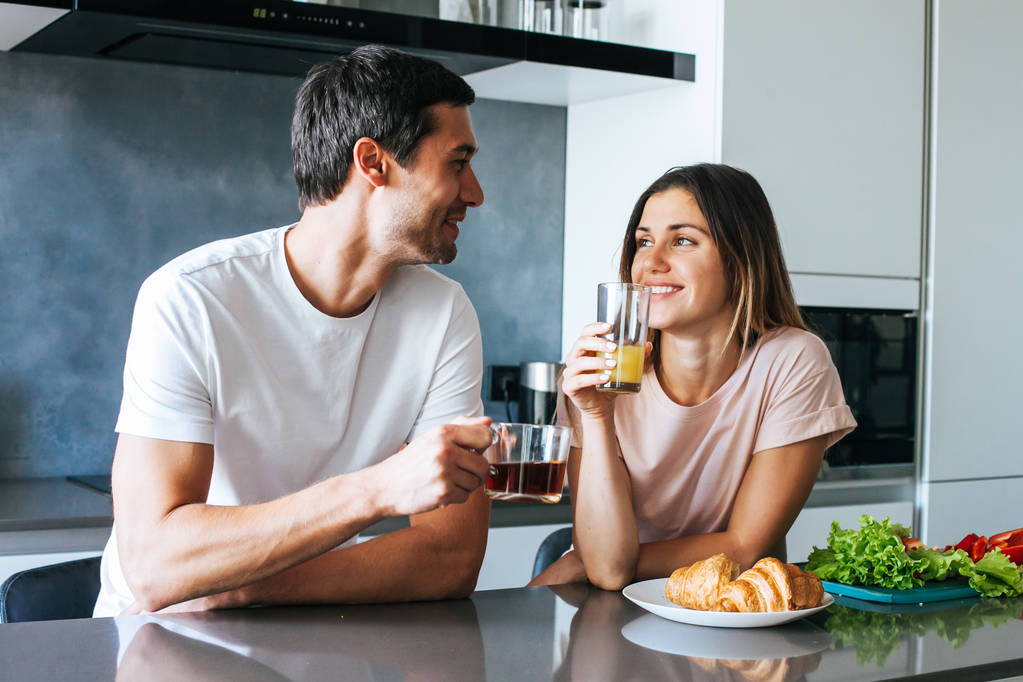Foto eines jungen Paares, das mit Kaffee in der Küche in den Tag startet - Foto, Bild