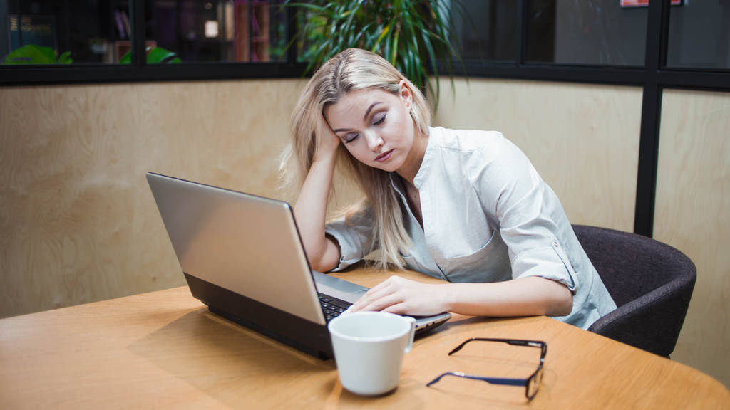 Mujer joven cansada con exceso de trabajo en la oficina en el portátil
 - Foto, imagen
