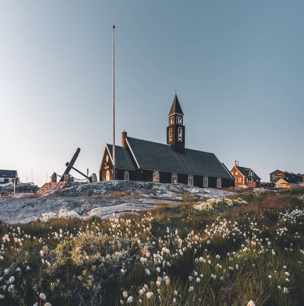 Stary wodden Zions Kościół w arktycznym mieście Ilulissat, z północą światło słoneczne i błękitne niebo w północnej Grenlandii - Zdjęcie, obraz