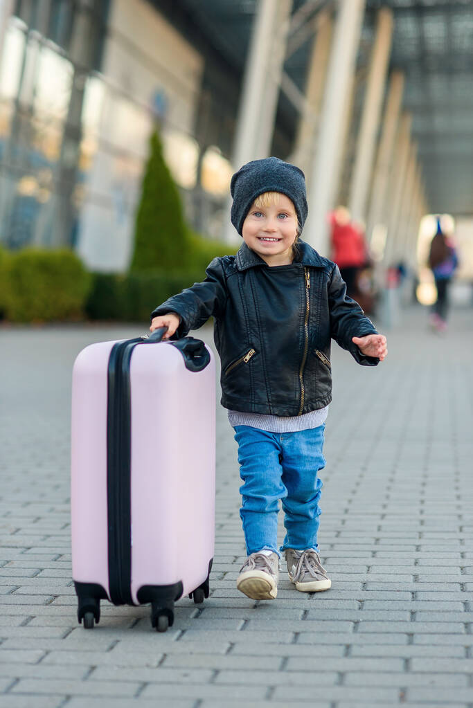 Όμορφη ευτυχισμένη κοπέλα ταξιδεύει με κομψή βαλίτσα. Μικρό παιδί ταξιδιώτη πηγαίνει στο ταξίδι από το αεροδρόμιο. - Φωτογραφία, εικόνα