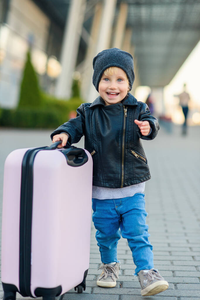 Красива щаслива дівчина подорожує зі стильною валізою. Маленький дитячий мандрівник вирушає в подорож з аеропорту
. - Фото, зображення