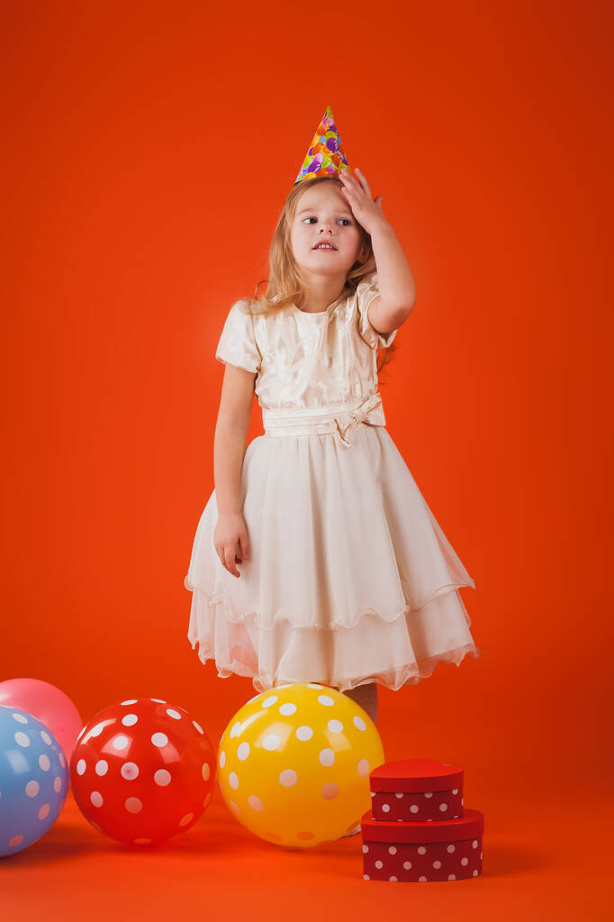 дівчина з подарунками і повітряними кулями на помаранчевому фоні
. - Фото, зображення