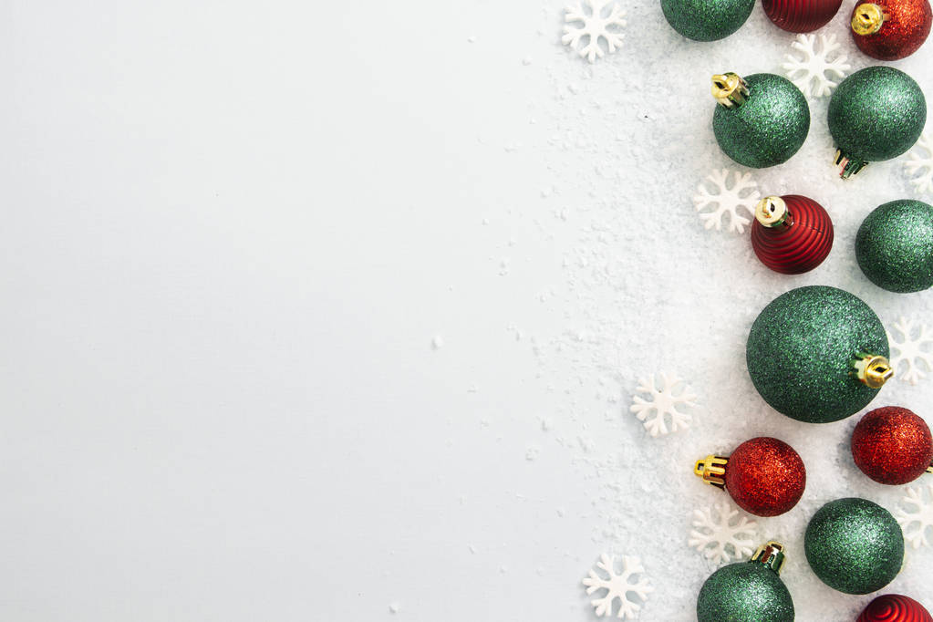 Χριστούγεννα αστραφτερά πράσινα και κόκκινα μπιχλιμπίδια, μπάλες απομονωμένες στο χιόνι. Χειμερινή αφηρημένη οριοθέτηση συνόρων. - Φωτογραφία, εικόνα