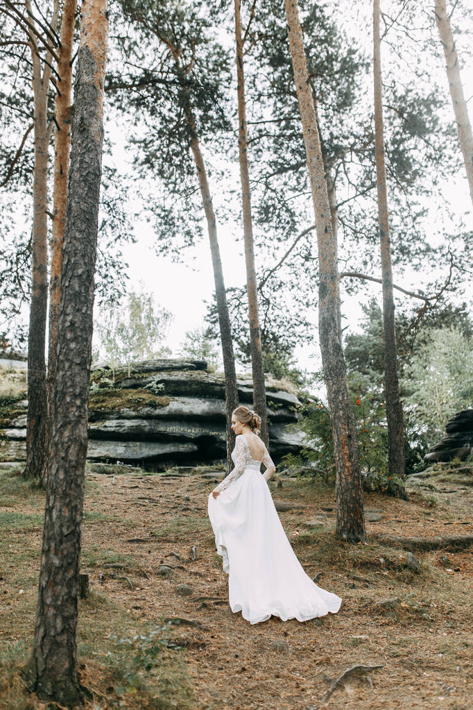 Elegáns ceremónia európai stílusban. Gyönyörű menyasszony fehér repülő ruha az erdőben.  - Fotó, kép