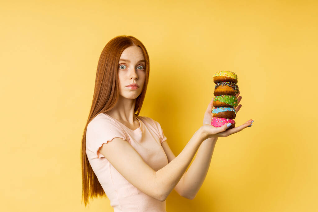 Joven hermosa mujer con rosquillas sobre fondo amarillo - Foto, imagen
