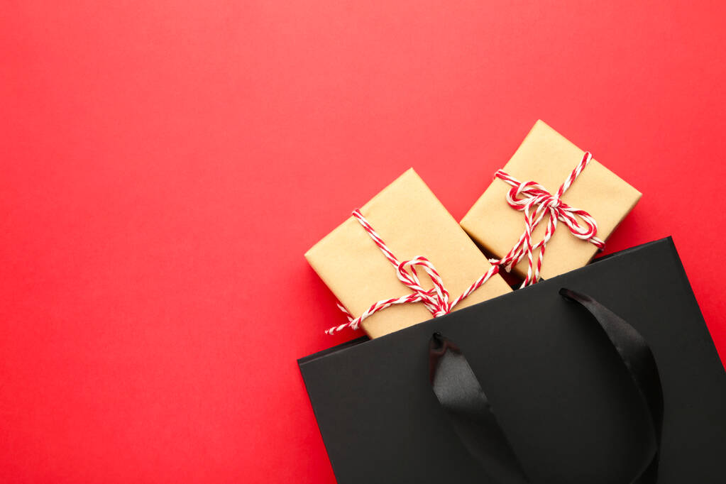 Bolso negro con regalos sobre fondo rojo
. - Foto, imagen