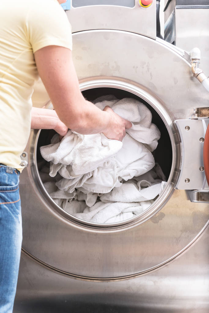 lavadora y una pila de toallas sucias y ropa de cama en el interior
 - Foto, Imagen