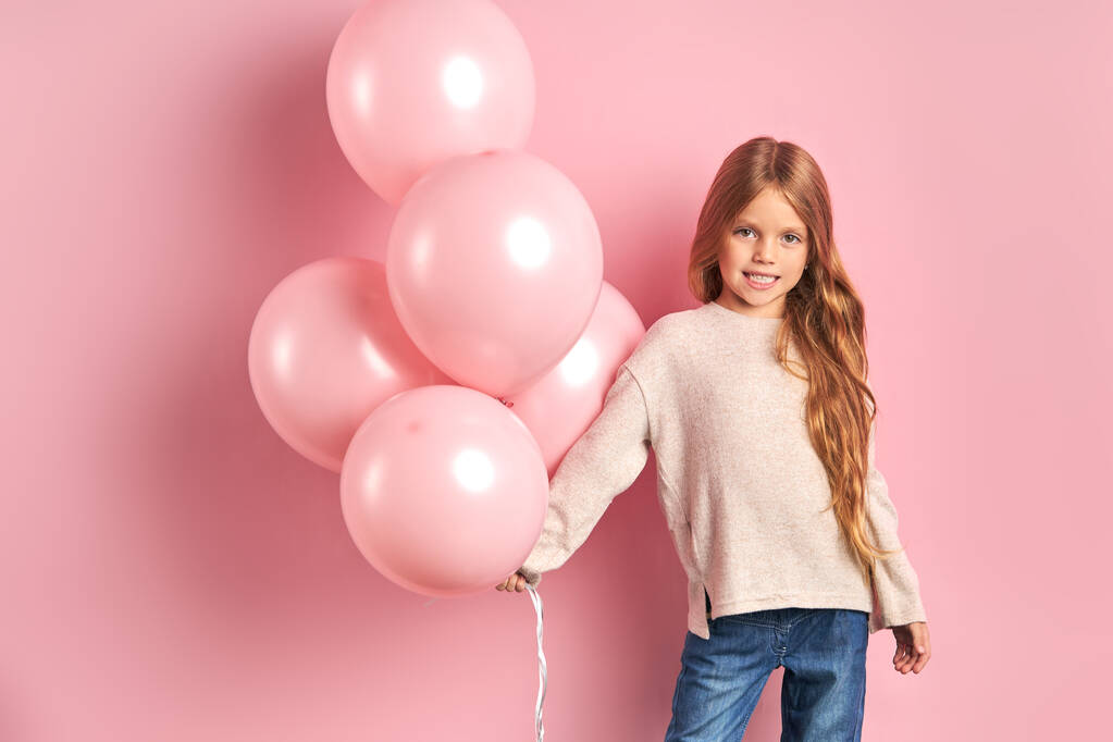 Criança branca sorridente posando com balões de ar
 - Foto, Imagem