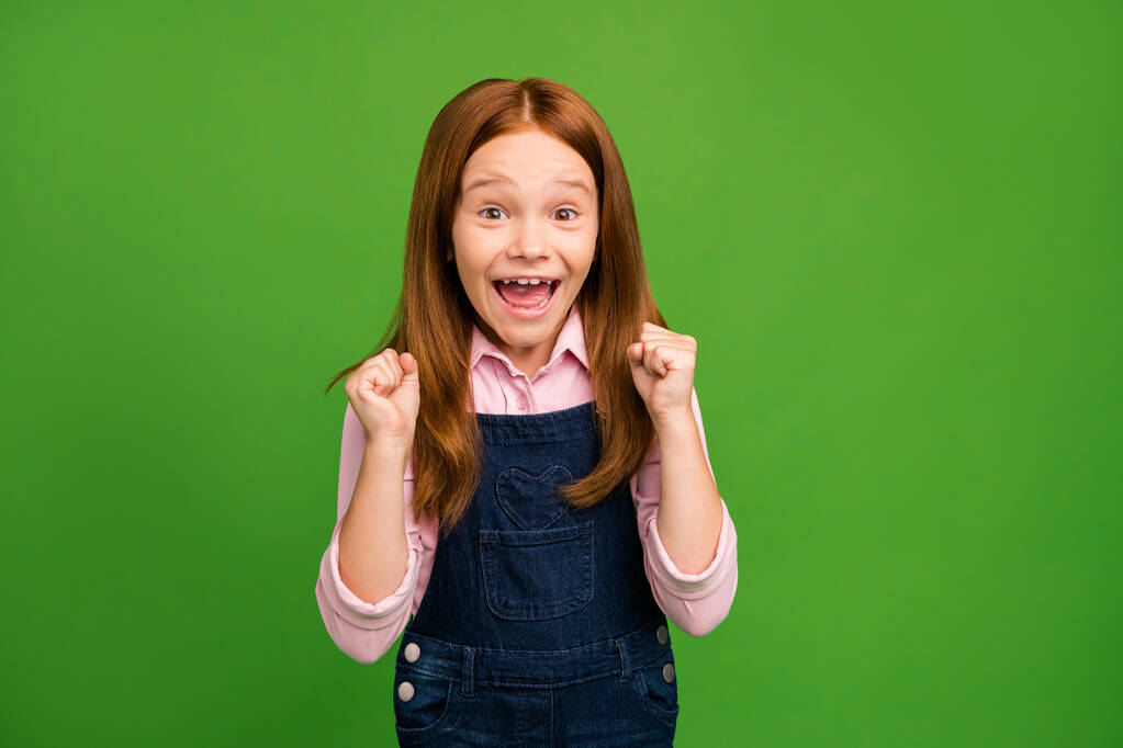 Photo of little foxy schoolchild in front of blackboard celebrating final examination best result in class raise fists wear denim overall pink shirt isolated green background - Photo, Image
