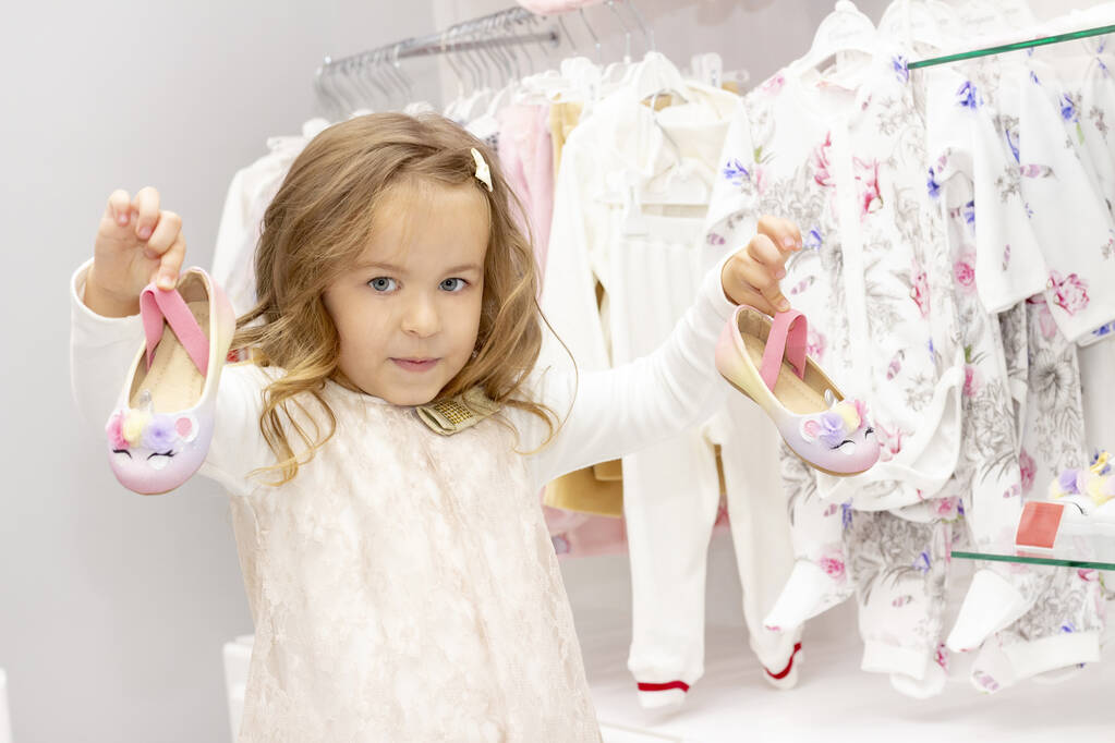 Zakupy. Zniżki. mała dziewczynka shopaholic. Dziewczyna wybiera buty do sukni. centrum handlowe, zakupy. Emocje - Zdjęcie, obraz