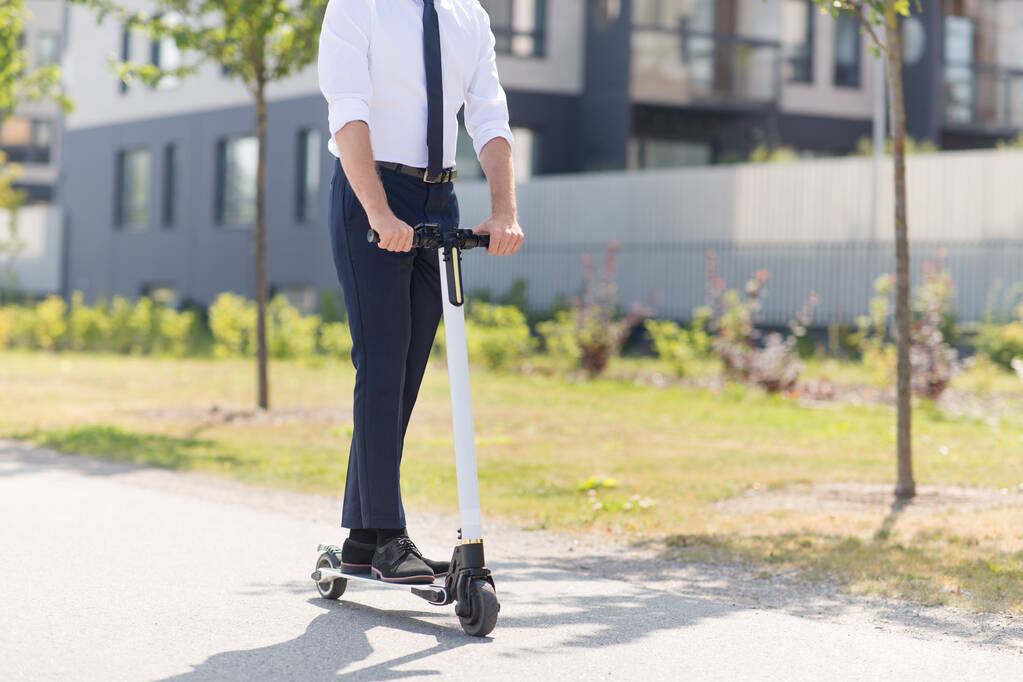 joven hombre de negocios montar scooter eléctrico al aire libre - Foto, imagen