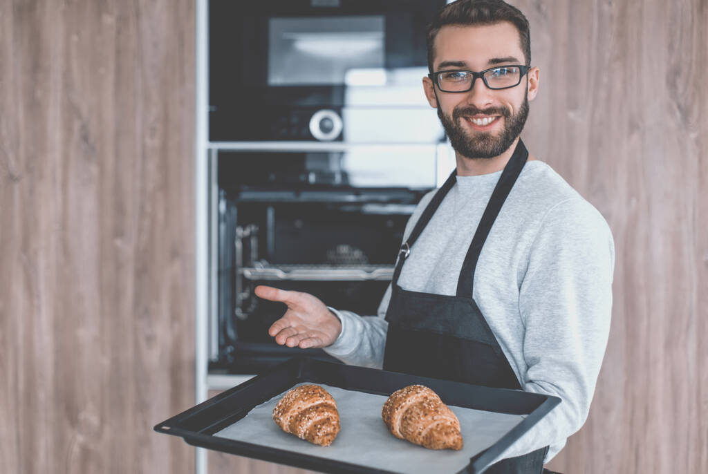 glimlachende man met een dienblad verse croissants - Foto, afbeelding