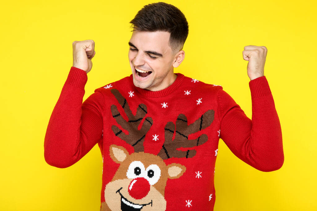 Красивый мужчина в красном рождественском свитере на желтом фоне
 - Фото, изображение