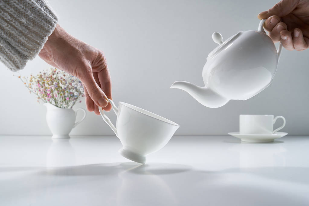 Skład z białą porcelanową herbatą na jasnoszarym tle z delikatnym bukietem kwiatów - Zdjęcie, obraz