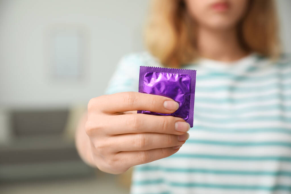 Žena držící kondom uvnitř, detailní záběr. Bezpečný sexuální koncept - Fotografie, Obrázek
