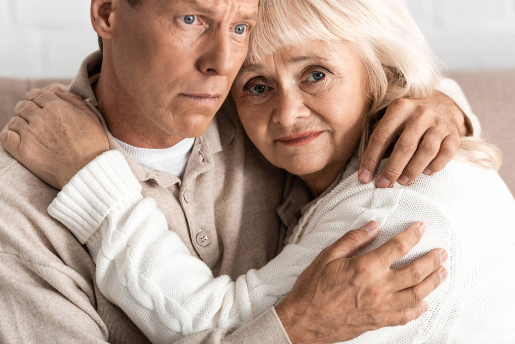 病気の夫と家で抱き合う動揺のシニア女性  - 写真・画像