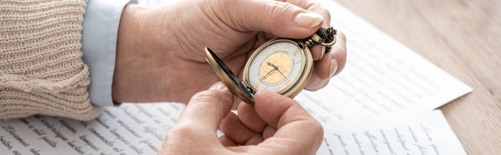 panoramatický záběr staršího muže držícího kapesní hodinky u papírů s písmeny  - Fotografie, Obrázek