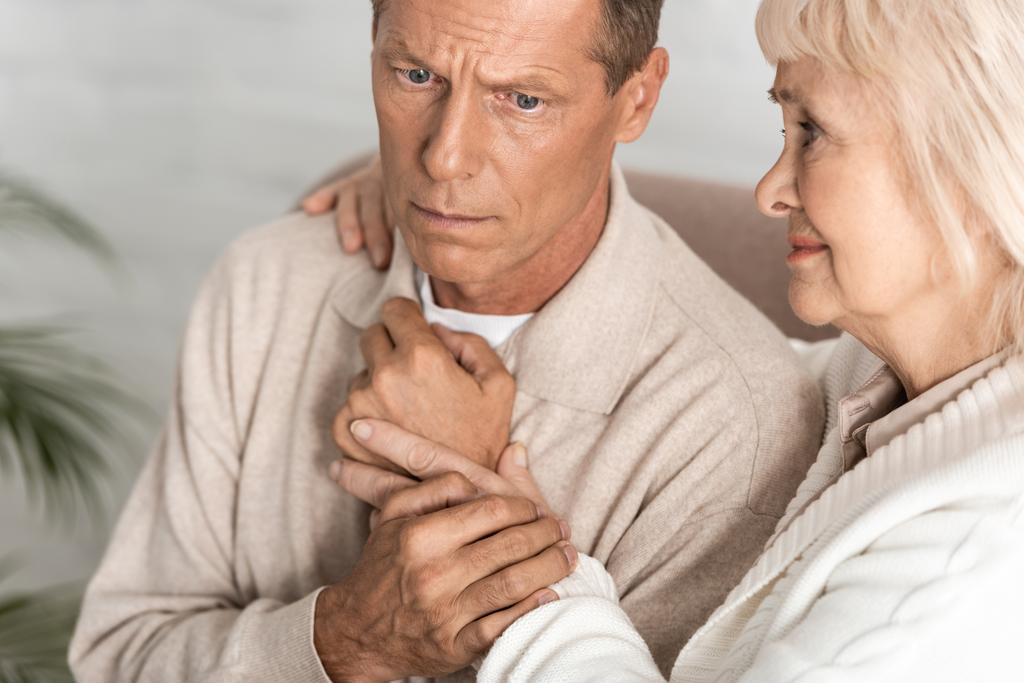 Traurige Rentnerin umarmt Ehemann mit Alzheimer-Erkrankung zu Hause  - Foto, Bild