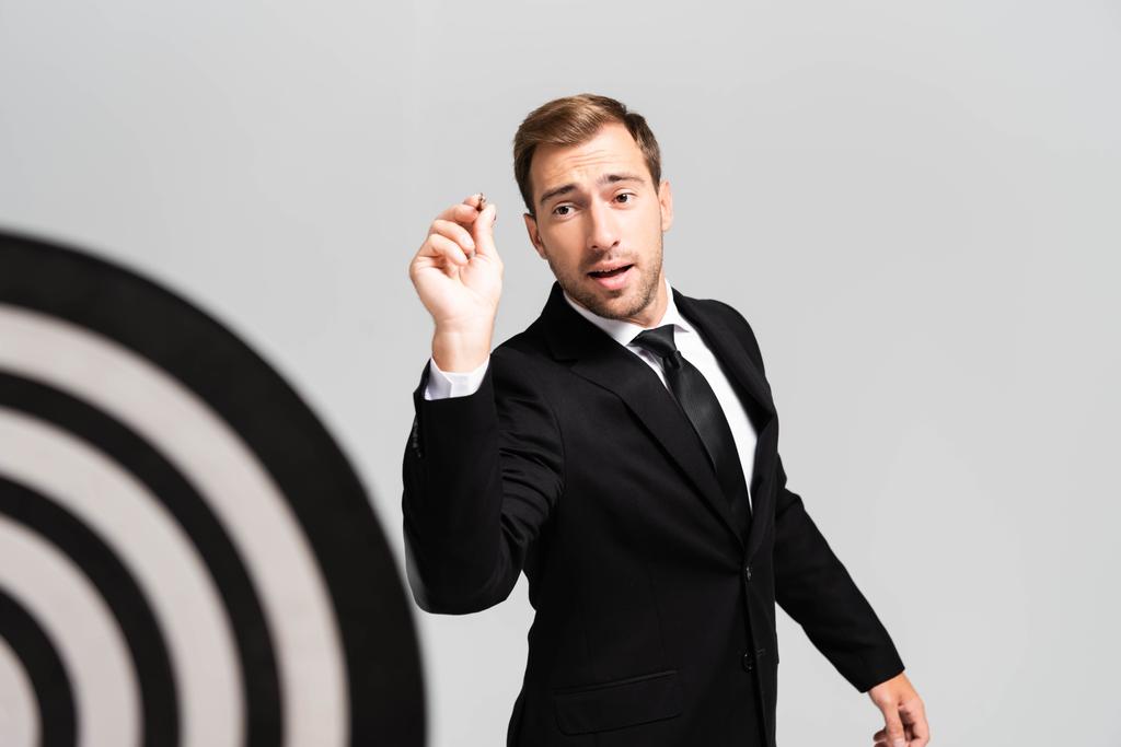 избирательный фокус бизнесмена в костюме играть в дартс изолированы на серый
 - Фото, изображение