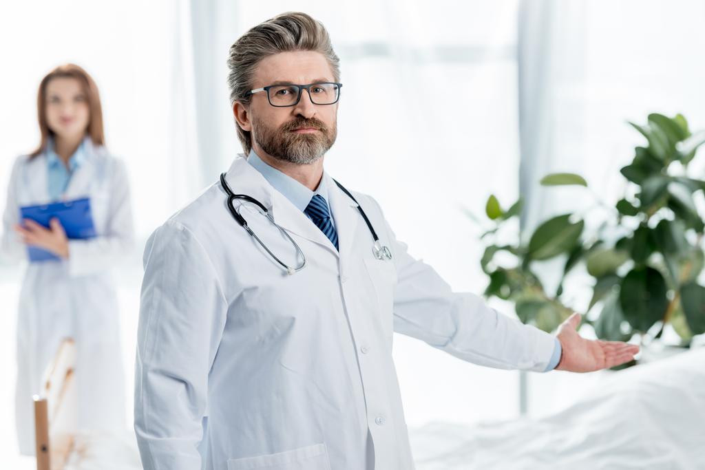 foco seletivo do médico em casaco branco apontando com a mão no hospital
  - Foto, Imagem