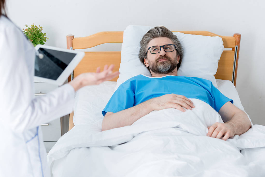 oříznutý pohled na lékaře držícího digitální tablet a pacienta ležícího v posteli v nemocnici  - Fotografie, Obrázek