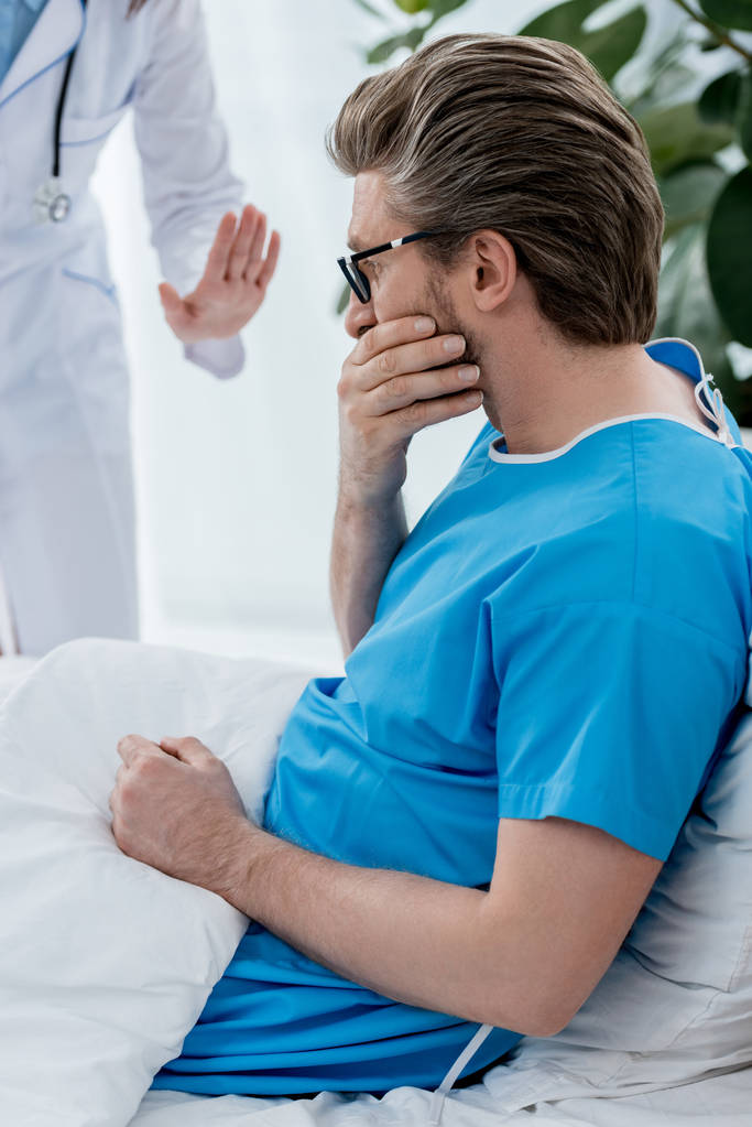 levágott kilátás orvos fehér köpenyben megnyugtatja szomorú beteg a kórházban  - Fotó, kép