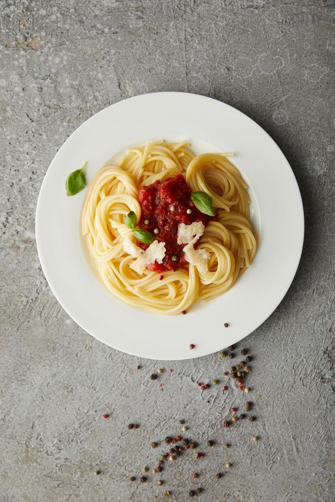 vista superior de deliciosos espaguetis con salsa de tomate en el plato en la superficie de textura gris
 - Foto, imagen