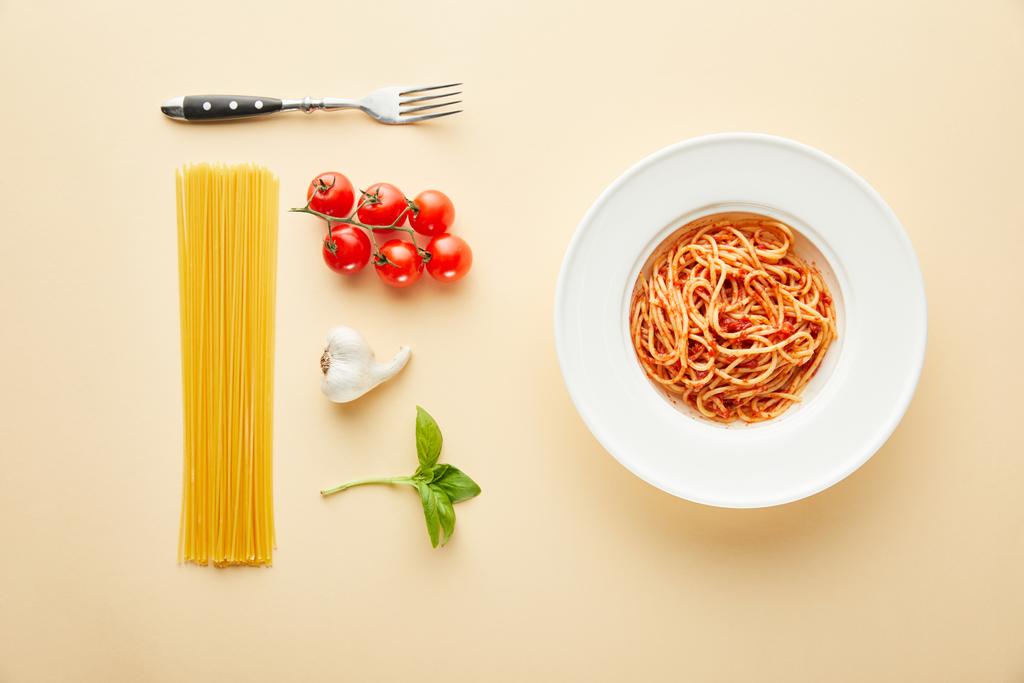 flache Lage mit leckeren Spaghetti mit Tomatensauce in Teller in der Nähe Gabel und Zutaten auf gelbem Hintergrund - Foto, Bild
